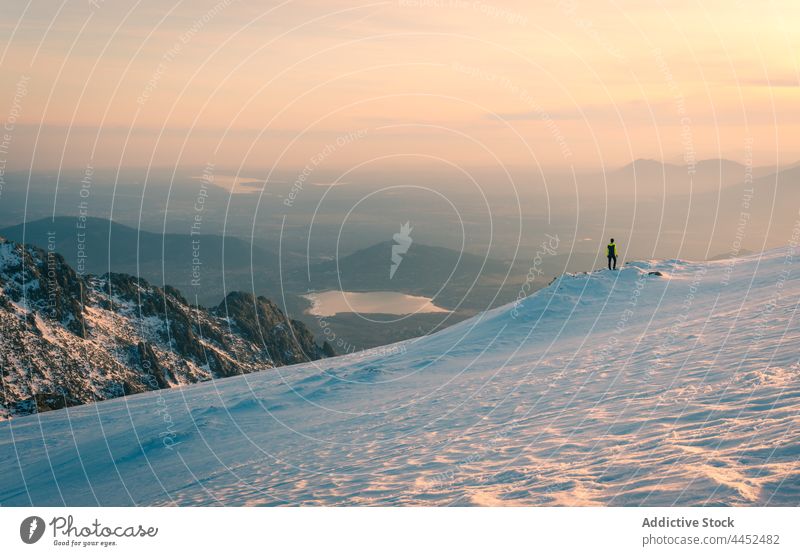 Wanderer auf verschneitem Berg unter buntem Himmel bei Sonnenuntergang stehend Person Reisender Berge u. Gebirge Hochland Schnee Ambitus Felsen Gipfel bewundern
