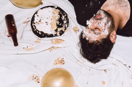 Betrunkener Mann liegt auf unordentlichem Tuch mit zerschlagenem Kuchen betrunken einschlagen Alkohol Party schlafen Geburtstag müde männlich Feiertag