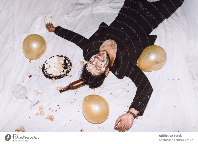Glücklicher Mann in zerschlagenem Kuchen mit geschlossenen Augen betrunken einschlagen Lachen Luftballon Schnaps Geburtstag Party unordentlich männlich Spaß