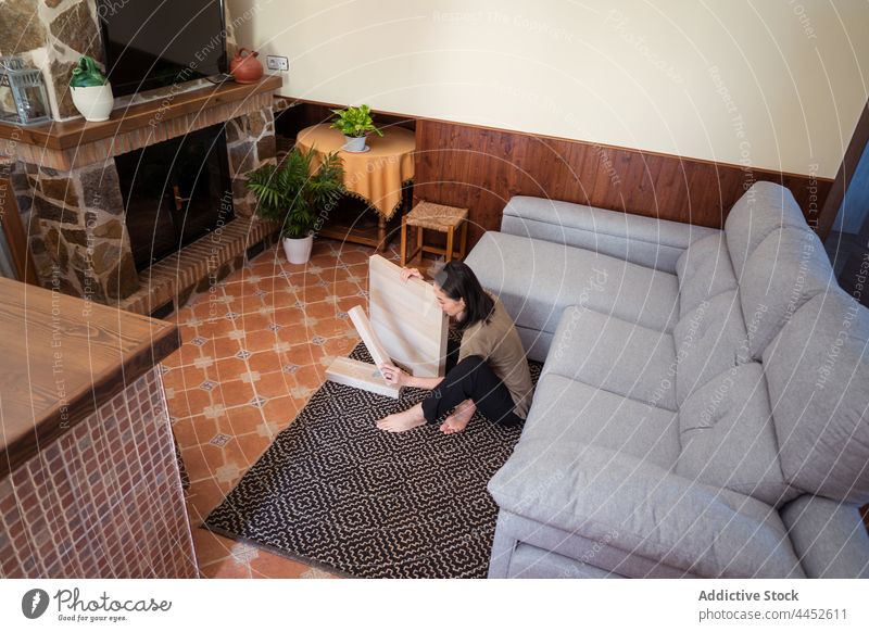 Asiatische Frau baut einen Tisch im Wohnzimmer zusammen versammeln achtsam Detailaufnahme diy Teppich Ornament Sofa heimwärts Raum Fokus Material Barfuß