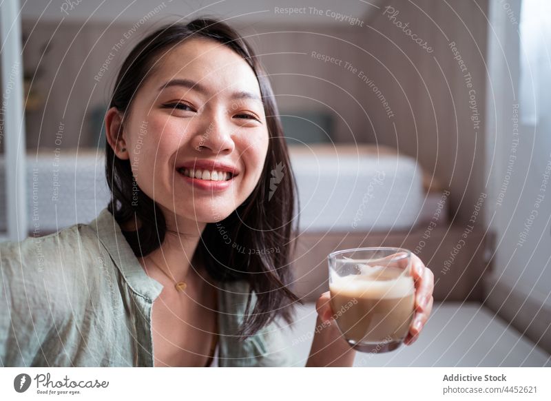 Glückliche asiatische Frau mit Kaffee zu Hause freiberuflich Schreibtisch heimwärts Porträt benutzend Apparatur Text Blogger Autor online tragbar Heißgetränk