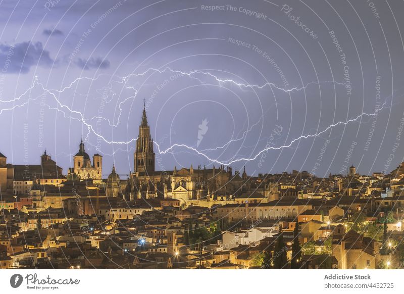 Stürmischer Himmel über der Stadt mit hohem alten Turm in der Nacht Großstadt Blitze Gewitter Unwetter Stadtbild wolkig Gebäude urban Toledo Spanien leuchten