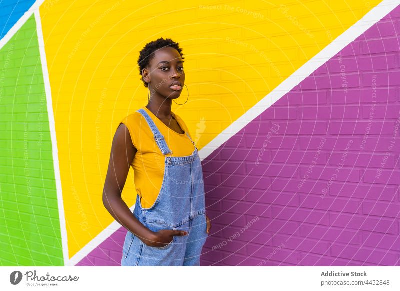 Schwarze Frau, die gegen eine bunte Wand steht positiv farbenfroh Spaß Optimist lässig sorgenfrei Vergnügen lebhaft spielerisch brünett ethnisch Afroamerikaner