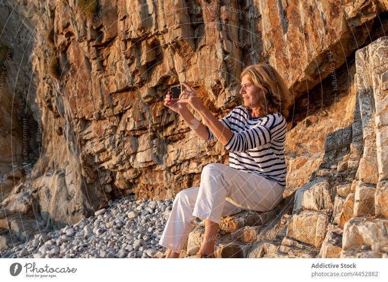 Frau fotografiert mit ihrem Smartphone an einer Klippe fotografieren Gedächtnis Moment Küste Natur Hochland benutzend Apparatur Gerät Funktelefon Ufer