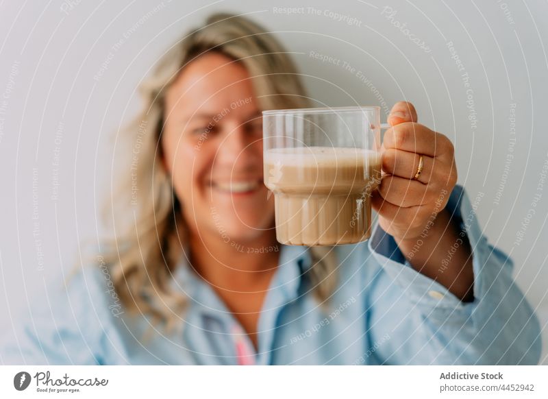 Fröhliche Frau mit einer Tasse aromatischem Milchkaffee Latte Kaffee Heißgetränk Getränk schäumen natürlich heiter angenehm Wittern Molkerei Bierschaum melken