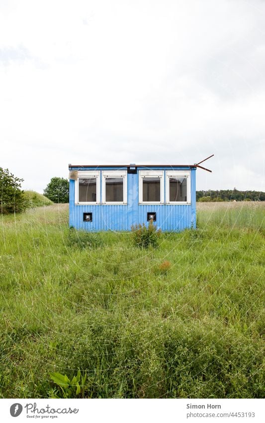 Containerhaus Wiese Unterkunft gestrandet Menschenleer Haus Wohnmobil Fenster provisorisch Flucht Versteck Gras blau Mauer trist Bauwerk