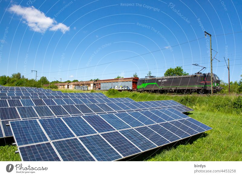 Freiland - Photovoltaikanlage neben einer Bahntrasse mit vorbeifahrendem Güterzug nachhaltig photovoltaik freilandphotovoltaikanlage grüner Strom Solarstrom