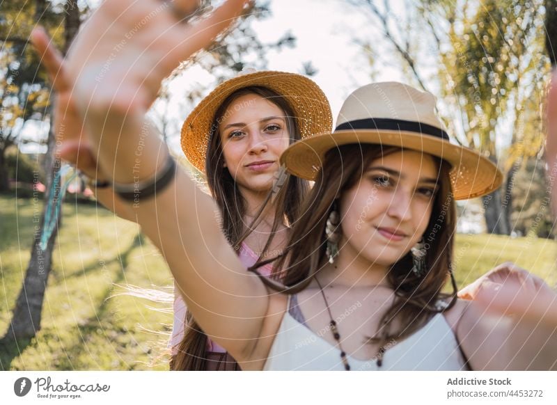 Lächelnde Freundinnen mit Strohhüten verbringen Zeit im Park Freundschaft Zeit verbringen Wochenende ausdehnen herzlich tausendjährig Porträt Teenager
