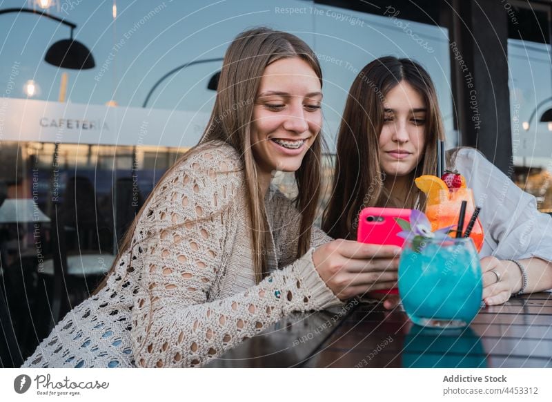 Freundinnen mit Cocktails beim Surfen auf dem Smartphone in einem Straßencafé Browsen Gedächtnis Moment Zeit verbringen Café benutzend Apparatur urban