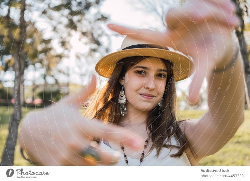 Teenager zeigt Rahmengesten im Sommerpark Foto Perspektive Bild Lächeln Klammer herzlich Park Porträt freundlich Strohhut Kleidungsstück Fotografie