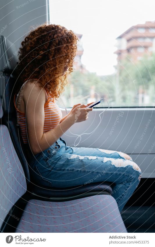 Fahrgast, der im Zug mit seinem Smartphone gegen das Fenster chattet Passagier plaudernd Internet online interessiert Arbeitsweg Frau benutzend Apparatur