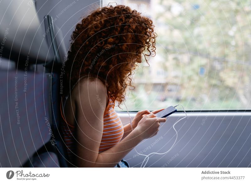 Fahrgast, der im Zug mit seinem Smartphone gegen das Fenster chattet Passagier plaudernd Internet online interessiert Arbeitsweg Frau benutzend Apparatur
