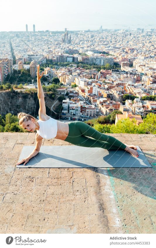 Schlanke Frau in seitlicher Unterarmstützhaltung auf dem Dach seitliche Unterarmplanke Yoga Gleichgewicht abstützen Arm angehoben Gesunder Lebensstil Vitalität