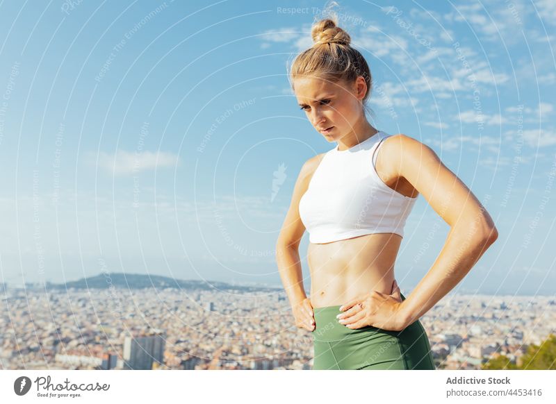 Sportlerin mit Blick auf die Stadt unter bewölktem Himmel Athlet Stadtbild Hand auf der Taille wolkig Revier Gesunder Lebensstil nachdenklich Pause Frau