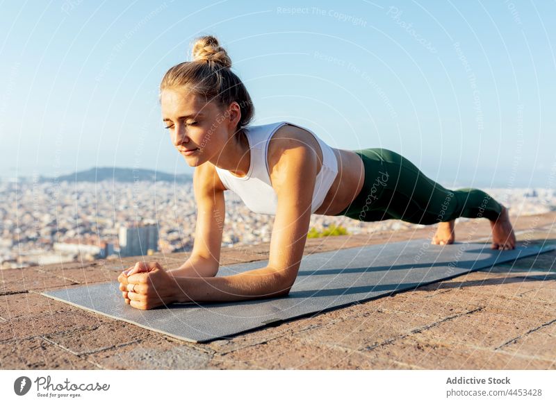 Konzentrierte Frau macht Unterarm Plank Pose auf Yoga-Matte Unterarmplanke Gleichgewicht abstützen Augen geschlossen Konzentration Wellness Vitalität