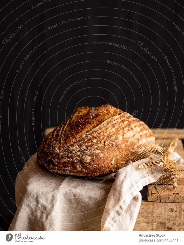 Sauerteig-Weizenbrot auf Handtuch auf dunklem Hintergrund Brot Kunstgewerbler Kruste frisch geschmackvoll Aroma gebacken ganz Müsli lecker Spitze gefaltet