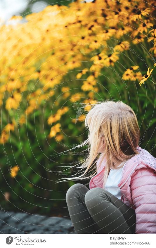 Wind weht einem jungen Mädchen vor einem Blumenfeld durch die Haare Wehen Kind gelb niedlich blond draußen Natürlich Kindheit
