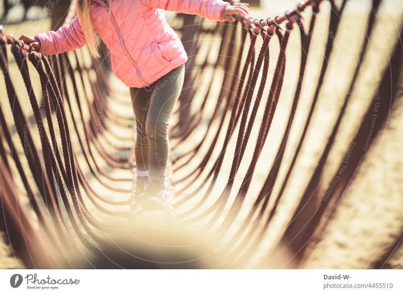 das Gleichgewicht halten - Kind auf einem Spielplatz balancieren Klettern Konzentration draußen Mädchen Kindheit