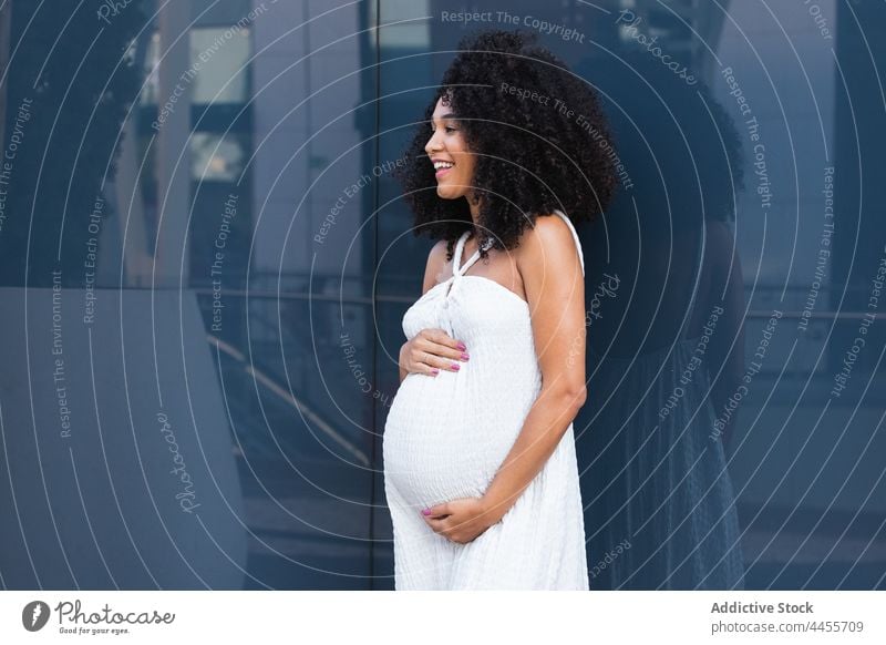 Lächelnde schwangere Frau im langen weißen Kleid Glück erwarten Körperhaltung genießen charmant Vorschein sorgenfrei Persönlichkeit Schwangerschaft froh