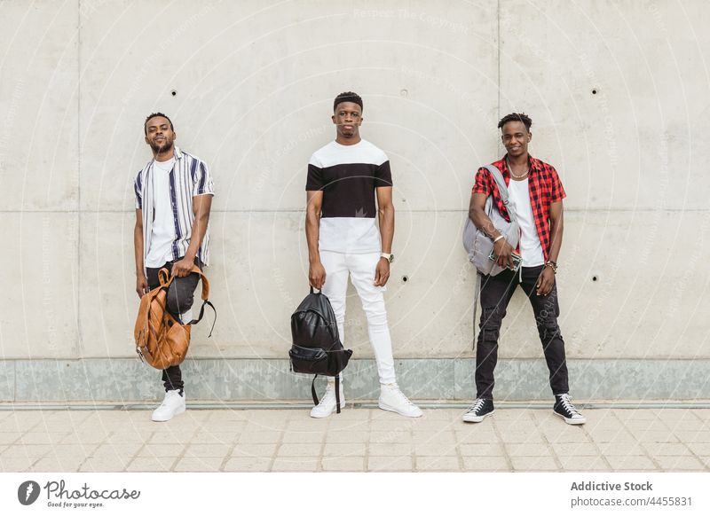 Schwarze männliche Freunde in stilvollen Outfits stehen in der Nähe einer Betonwand Männer cool Stil maskulin trendy modern selbstbewusst Individualität