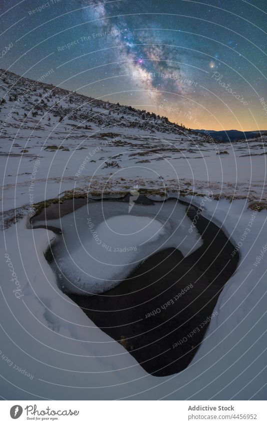 Verschneite Pfütze aus Eiswasser unter nächtlichem Sternenhimmel mit Milchstraße Schnee Berge u. Gebirge Hochland Natur Winter Landschaft Gelände dreckig Kamm