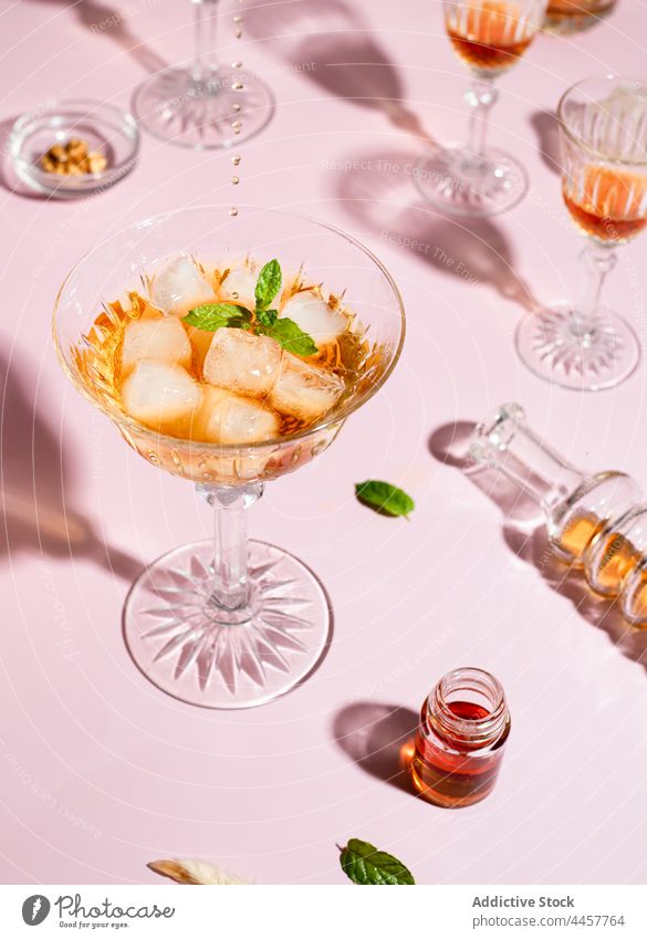 Becher mit Cocktail mit Basilikum Glas Whiskey trinken Garnierung Kelch kalt Erfrischung Alkohol dienen Würfel Tisch Eis Getränk Glaswaren Kraut Blatt glänzend