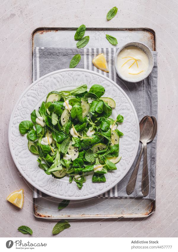 Minze und Spinatsalat gegen Zitronensauce auf grauem Hintergrund Salatbeilage Salatgurke gesunde Ernährung Saucen Vitamin Gemüse Mittagessen Portion lecker