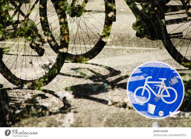 Räder auf der Straße mit dem Verkehrszeichen für Radweg Fahrrad Sonnenlicht Doppelbelichtung Silhouette Asphalt Blätter Schatten Reaktionen u. Effekte Mobilität