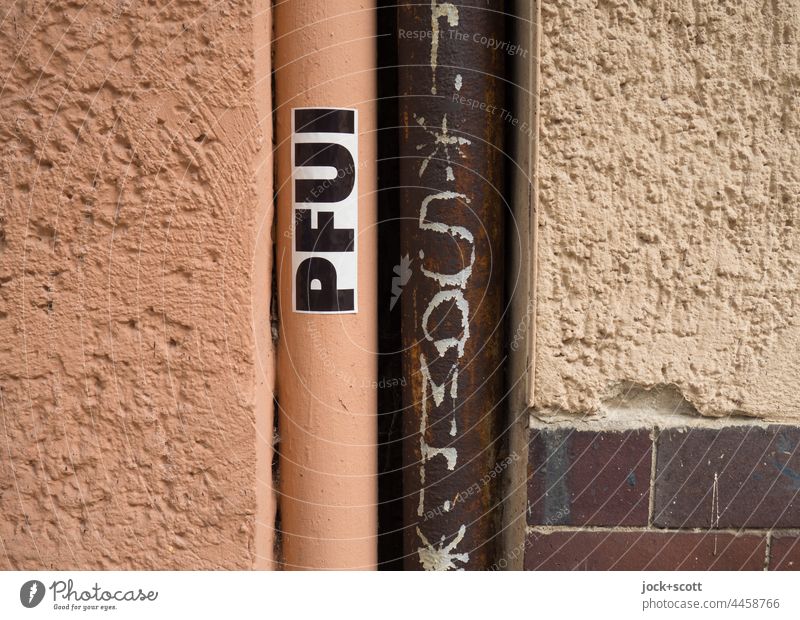 Pfui / Putz neben Regenrohr oder Fallrohr Straßenkunst Röhren Wand Wort Deutsch Kreativität Aufkleber Großbuchstabe Typographie Detailaufnahme
