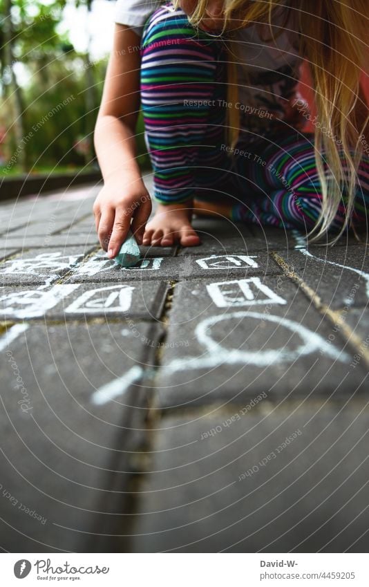 Kind malt mit Straßenmalkreide auf dem Boden Kreide malen Mädchen Kreativität beschäftigung draußen Kindheit Spielen