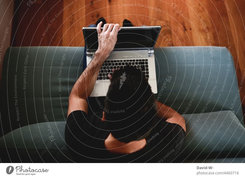 Mann packt seinen Laptop aus arbeiten Sofa Homeoffice gemütlich Mobilität zu Hause digital lernen Notebook