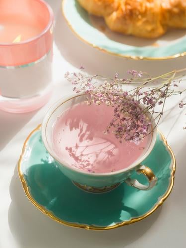 Nahaufnahme von rosa Blumen Tee in türkisfarbenen Teetasse auf sonnigen Frühstückstisch abschließen Tisch Teezeit authentisch Hintergrund Tasse trinken geblümt