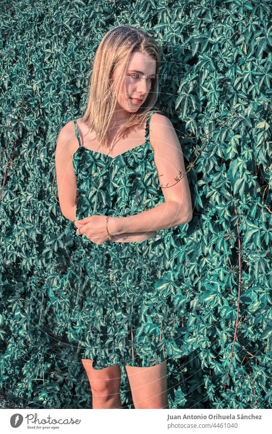 Blondes Mädchen in einem grünen Kleid mit Blättern in einem natürlichen Hintergrund bizarr frisch Glamour lange Haare geblümt Zauberei u. Magie Menschen