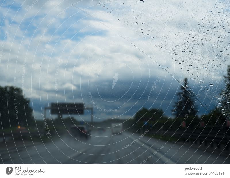 auf der Autobahn bei starken Gewittern Regen schlechtes Wetter Gewitterwolken Himmel Windschutzscheibe Wassertropfen Unwetter Wolken Verkehrswege Autofahren