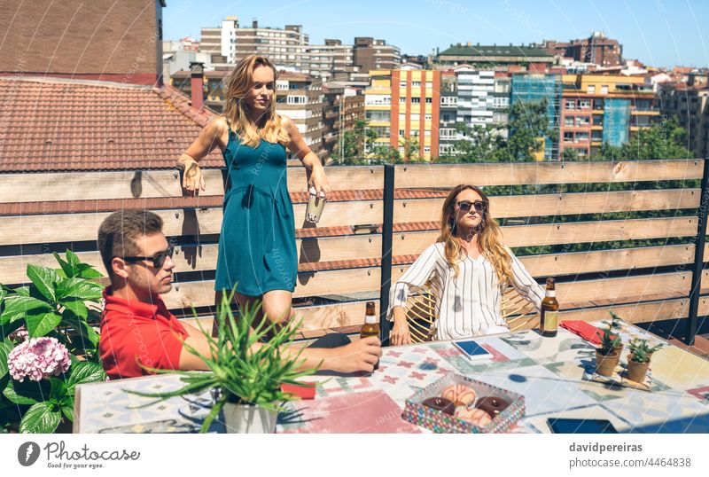 Freunde trinken auf einer Terrasse Menschengruppe Sonnenbad Bier jung Textfreiraum Dachterrasse ernst elegant Kaffee Flasche Frau männlich Kaukasier Sommer