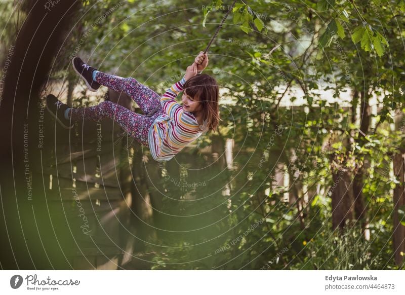 Glückliches Mädchen auf einer Baumschaukel im Garten Aktion Lachen heiter außerhalb Spielplatz Freizeit spielerisch Bewegung freudig Freiheit frei Tag Aufregung