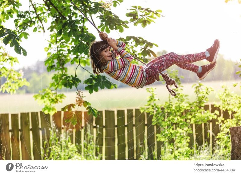 Glückliches Mädchen auf einer Baumschaukel im Garten Aktion Lachen heiter außerhalb Spielplatz Freizeit spielerisch Bewegung freudig Freiheit frei Tag Aufregung