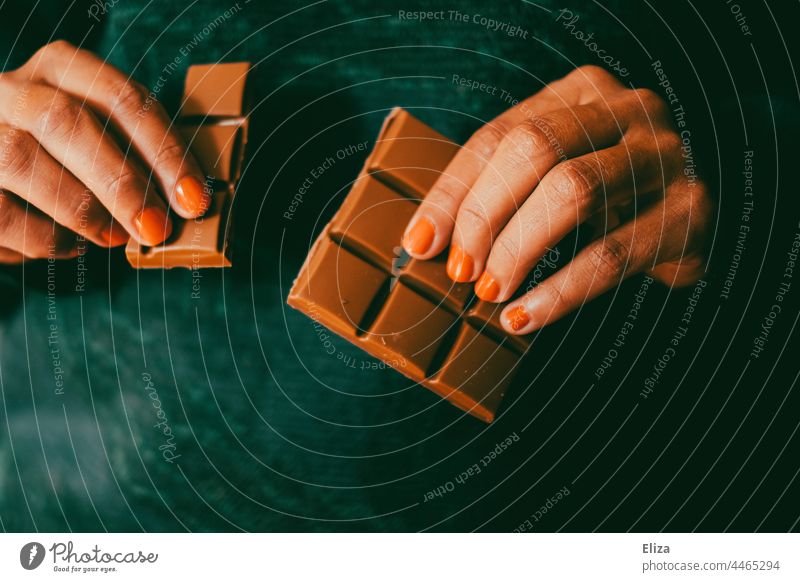 Eine Frau bricht eine Reihe von einer Schokoladentafel ab abbrechen naschen Hände braun Süßwaren Naschzeug
