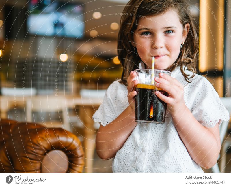Lächelndes Mädchen trinkt erfrischendes Getränk in einem Cafe trinken Karbonat Erfrischungsgetränk Soda Glas kalt Stroh süß Durst charmant Kindheit lecker