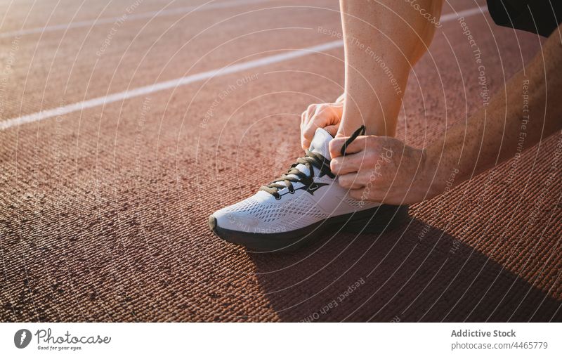 Crop-Sportler beim Anziehen der Turnschuhe auf der Strecke Läufer angezogen vorbereiten modern Stil Leichtathletik professionell Mann Training Athlet Schuhe