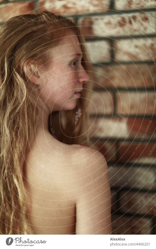 Nahaufnahme einer nackten jungen Frau mit Sommersprossen und roten Haaren, die vor einer Backsteinmauer steht Porträt Nähe Ausstrahlung Ruhe kraftvoll hübsch