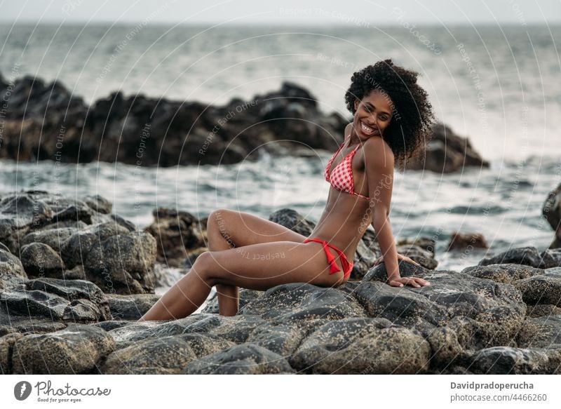 Frau sitzt auf einem Felsen am Meeresufer ethnisch Insel Seeküste schön Bikini passen Lächeln Afrikanisch sexy Kap Verde Feiertag horizontal Glück schwarz