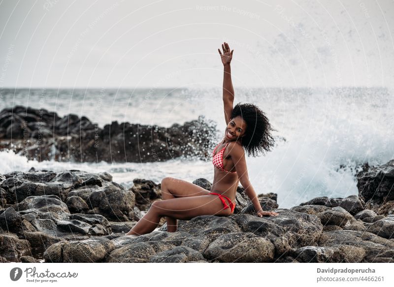 Frau sitzt auf einem Felsen am Meeresufer ethnisch Insel Seeküste schön Bikini passen Lächeln Afrikanisch sexy Kap Verde Feiertag horizontal Glück schwarz