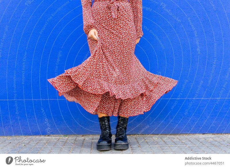 Frau stehend gegen blaue Wand bei Tageslicht Stil Straße Kleid trendy Outfit Bürgersteig Straßenbelag Laufsteg tagsüber lässig feminin Individualität urban