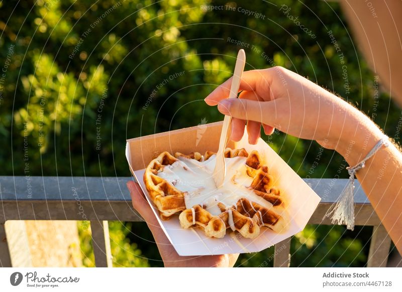 Anonyme Person genießt leckere Waffeln vor dem Hintergrund der Berge im Sonnenschein essen Dessert Leckerbissen Sahne gepeitscht süß Imbissbude Berge u. Gebirge