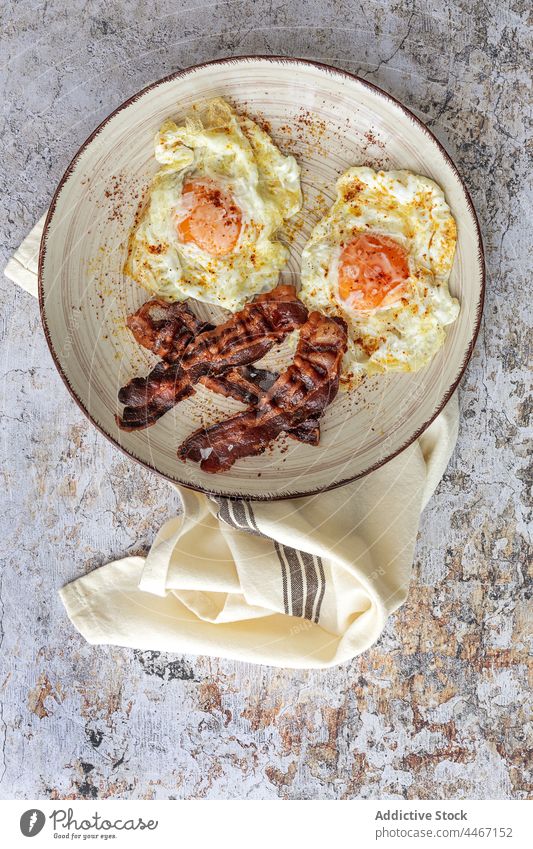 Leckeres Frühstück mit Spiegeleiern und Speckscheiben Ei gebraten Lebensmittel Mahlzeit Nährstoff geschmackvoll Teller Handtuch Ornament Streifen Weizen