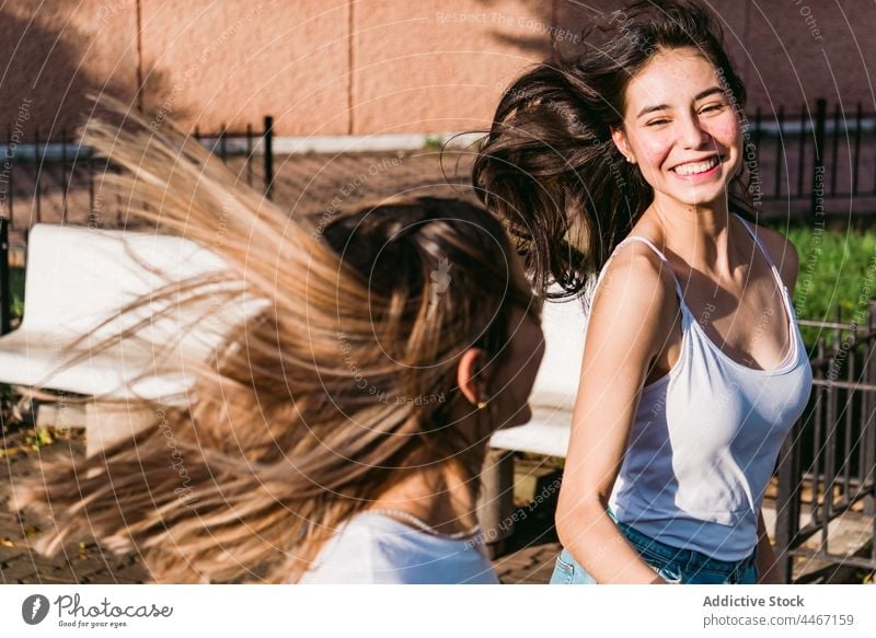 Glückliche Freundinnen mit fliegenden Haaren haben Spaß auf der Straße fliegendes Haar Spaß haben sorgenfrei heiter Freundschaft Zeit verbringen interagieren
