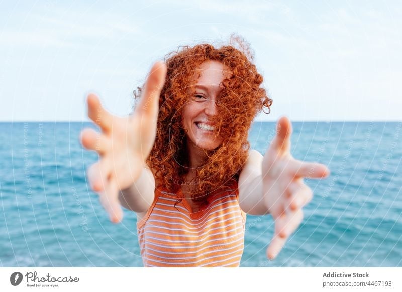 Fröhliche Frau, die sich am Meeresufer die Hände reicht Glück blau MEER Wind Ufer froh Urlaub Feiertag Freude sich[Akk] melden heiter lange Haare Rotschopf
