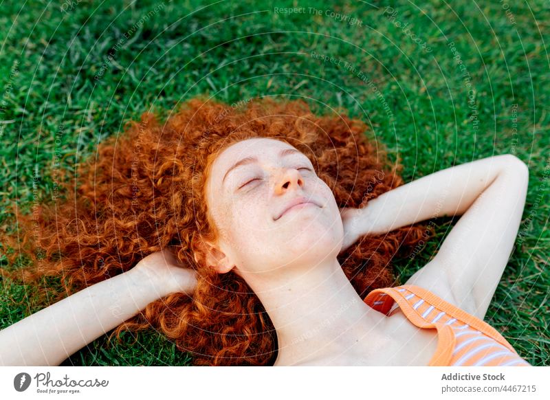 Fröhliche Frau mit Händen hinter dem Kopf im Gras liegend Glück sich[Akk] entspannen Individualität Rasen Kälte genießen Freude Vergnügen heiter Vorschein froh