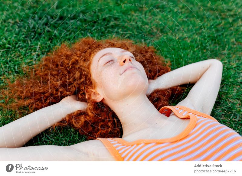 Fröhliche Frau mit Händen hinter dem Kopf im Gras liegend Glück sich[Akk] entspannen Individualität Rasen Kälte genießen Freude Vergnügen heiter Vorschein froh